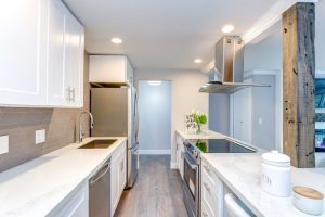 Parasol white small kitchen with stainless steel appliances in modern condo.